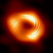 Ein orangefarbenes, donutförmiges Objekt vor einem schwarzen Hintergrund. Drei Kleckse auf dem Donut sind besonders hell. Dünne, wirbelnde Linien, die den Donut überlagern, drehen sich spiralförmig um das zentrale Loch des Donuts.