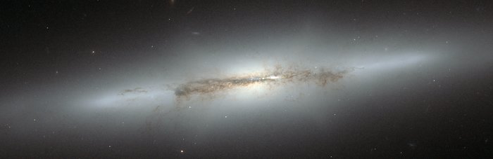 Pohled na galaxii NGC 4710 a její výduť ve tvaru X dalekohledem HST
