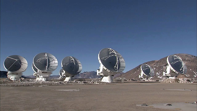 Pan over ALMA array of antennas on Chajnantor as they move in unison